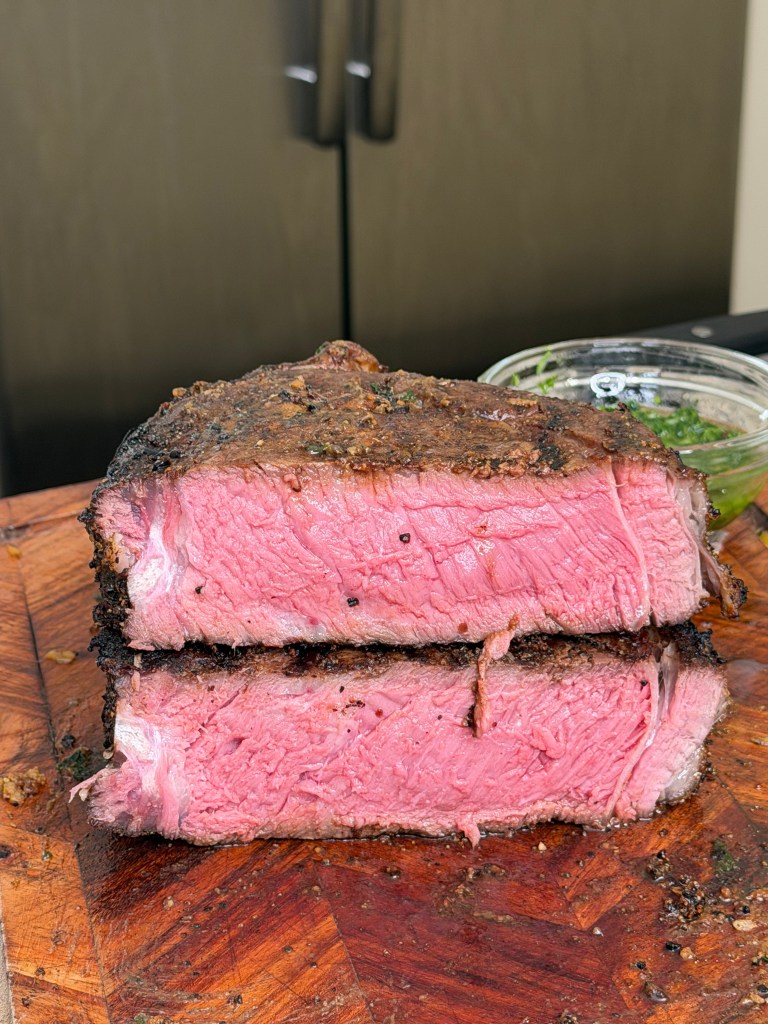 Sliced medium-rare roast beef on a wooden cutting board, showcasing a pink interior and browned exterior.